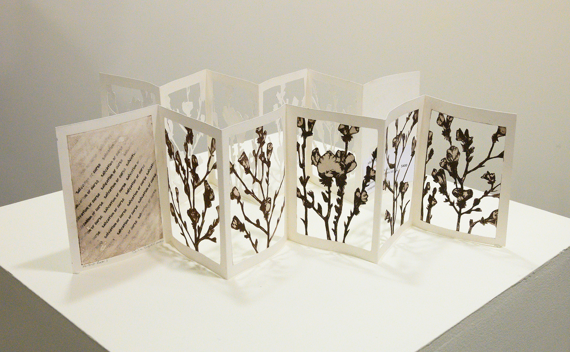 Folded concertina style artist book by Julie Bignell, featuring 5 panels with hand cut b&w flowers and 1 panel with text