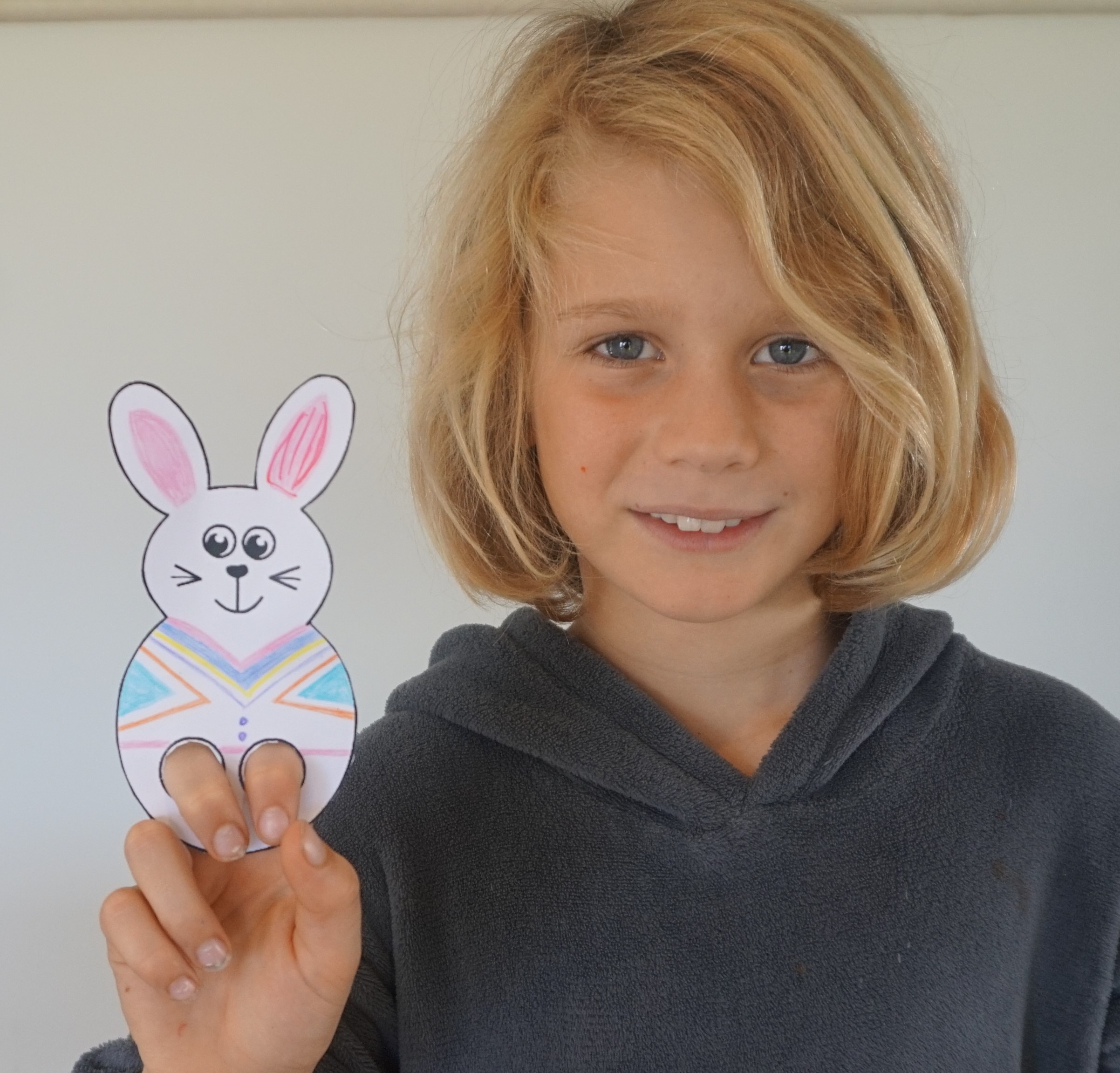 Boy demonstrating finished bunny puppet.