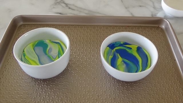 Marbled colourful polymer clay inside ceramic bowls on oven tray